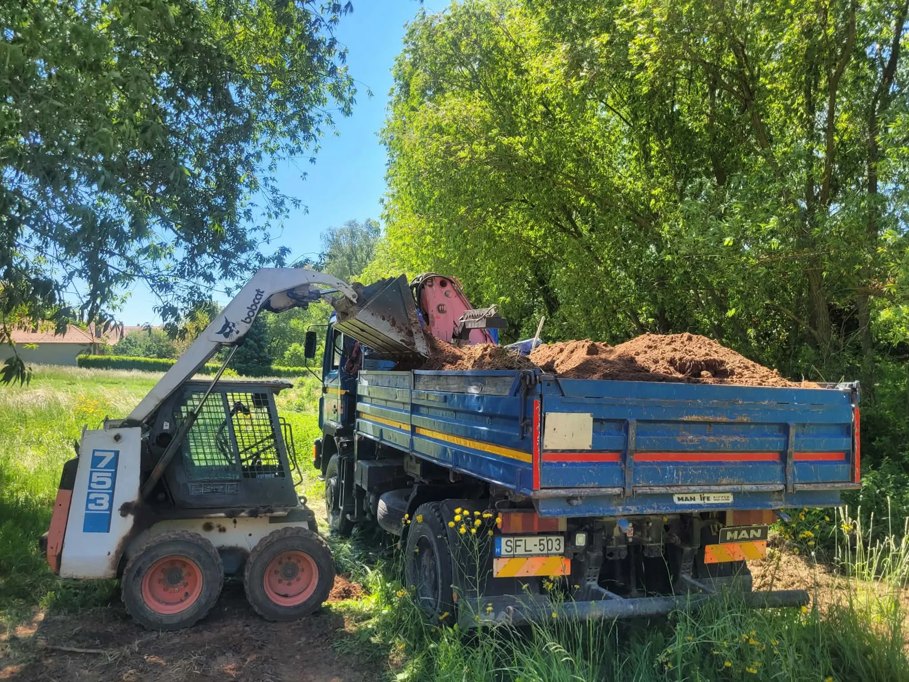 Bobcat rakodógép teherautóra rakodja a földet